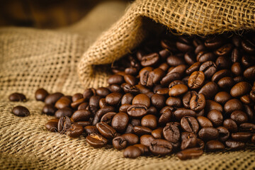 Rich dark coffee beans spilling from a rustic burlap sack