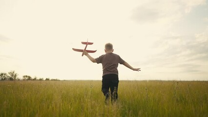 a little boy running in the park on the grass with a toy airplane in his hands. happy family childhood dream concept. a small son runs across the field in the forest with lifestyle a toy