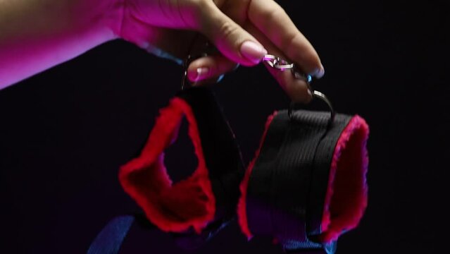 In women's hands, soft handcuffs for erotic play. The girl is holding a sex shop toy Sex toy clitoral vibrator