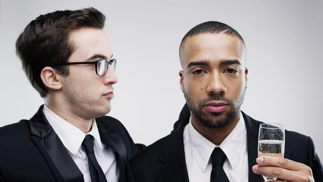 Young men, dancing and champagne in studio for goofy game, joke and movement for crazy humour. Friends, diversity or moody at celebration with alcohol or bored at party event by white background