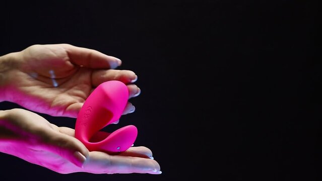 A girl runs her hand over a sexy adult toy. The girl is holding a sex shop toy Sex toy clitoral vibrator