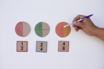 Math teaching materials about fraction. Hand hold pen. Circle paper  show parts of color separation. Concept, education. DIY craft as teaching aid in Math subject.                                