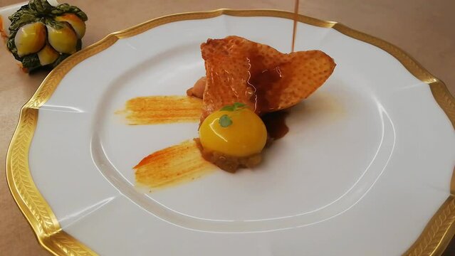 皮をパリッパリにした鶏肉のソテーと新鮮な平飼い卵にソースをかける