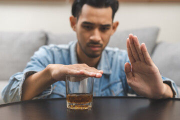 Alcoholism, depressed asian young man refuse, push out alcoholic beverage glass, drink whiskey,...