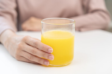 Close up young woman hand holding glass of water after putting or dropping yellow effervescent tablet, pain pill, painkiller medicine, aspirin for treatment, take vitamin c for hangover, health care.