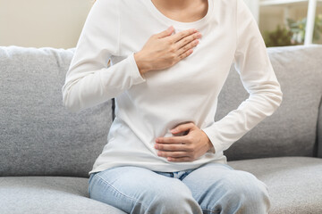 Acid reflux disease, suffer asian young woman have symptom gastroesophageal, esophageal, stomach ache and heartburn pain hand on chest from digestion problem after eat food, Healthcare medical concept - obrazy, fototapety, plakaty
