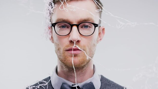 Man, portrait and silly string in party, birthday and serious on studio background with face on photobooth. Celebration, guy and glasses for headshot, looking and male person with spray and young