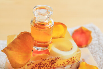 A bottle of perfume, rose petals and bar of handmade soap in the bathroom.