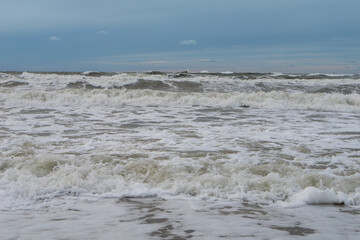 seashore on a cloudy day, strong waves, storm on the horizon, dark blue sky