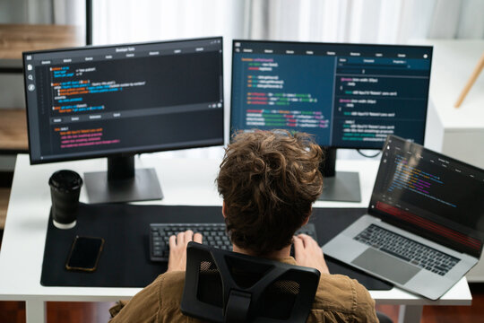 IT developer working online software development on pc monitors at modern home office on coding application screens, creating updated latest program firmware information version concept. Gusher.