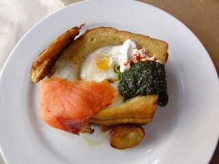 Breakfast with fried egg, smoked salmon and spinach on white plate
