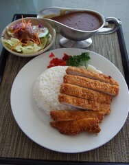 Serving of porkchops, rice and vegetables for side dish.