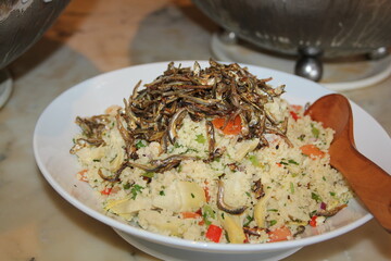 Fried rice with dilis or small fried fish in a white plate.