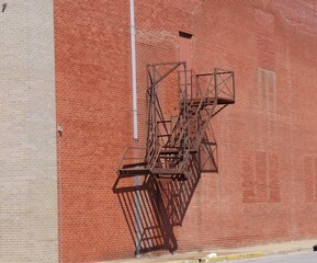 Old metal fire escape on the red brick wall of the building.