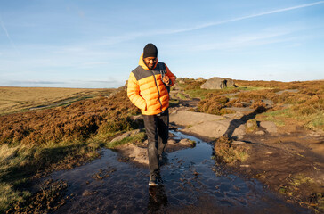 happy handsome man tourist with backpack hiking and enjoying mountains landscape at sunset in England. A trip to the mountains with a backpack. Enjoy hiking and exploring new places concept