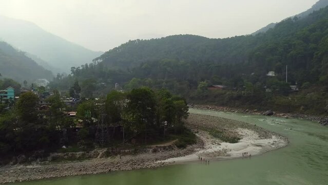 Aerial view above the Tista river, in a valley between mountains and Indian forest, on a sunny day, in Sikkim, India.