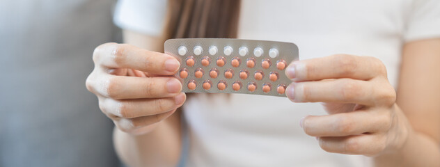 Contraception and pregnancy, menstruation concept, birth control pills asian young woman hand holding hormonal oral contraceptive medicine, take pharmaceutical to prevention, safe virus sex disease. - obrazy, fototapety, plakaty