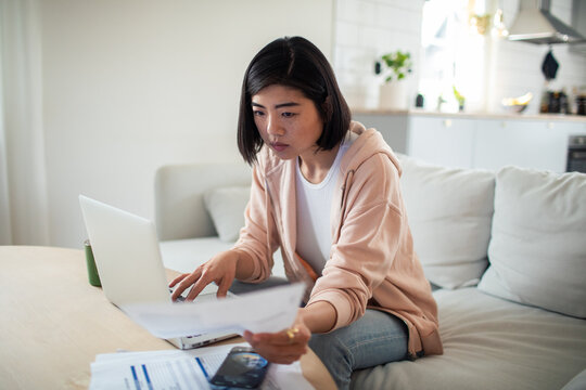 Worried young woman checking bills and finances at home
