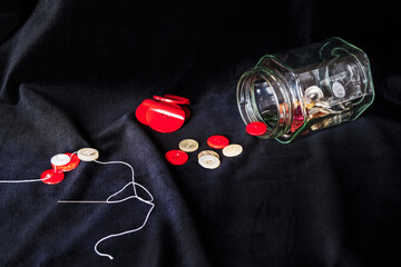 Still life, glass jar and buttons on a black velvet background