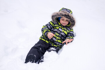Fototapeta na wymiar little child playing in the snow in winter