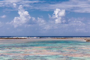 French Polynesia, Tikehau atoll. Abstract composition of white clouds and pink coral reef in full...