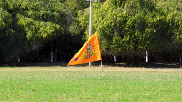 holy saffron flag with lord rama idol waving at ground with green tree background at day