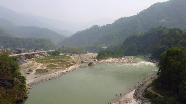 Aerial view above the Tista river, in a valley between mountains and Indian forest, on a sunny day, in Sikkim, India.