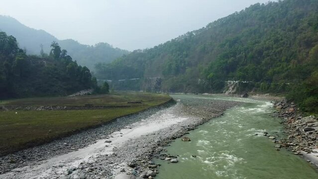 Aerial view above the Tista river, in a valley between mountains and Indian forest, on a sunny day, in Sikkim, India.