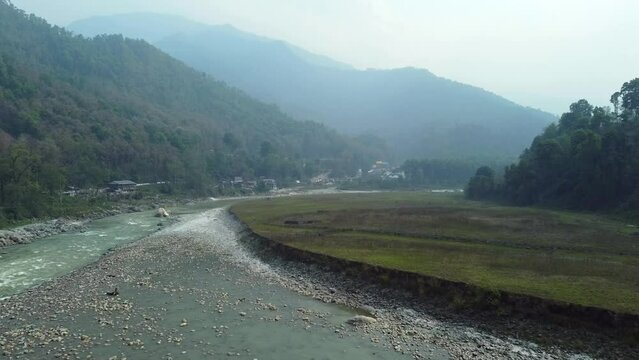 Aerial view above the Tista river, in a valley between mountains and Indian forest, on a sunny day, in Sikkim, India.