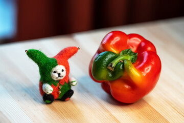 felt toy clown and funny shaped paprika on a wooden table