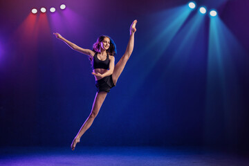 young performer of modern choreography dancing in the spotlights on a black background.