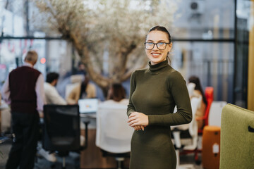 A confident, successful professional standing in a modern office. The business person looks happy,...