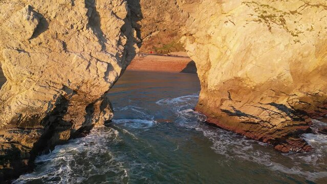 The sun goes down on the Jurassic coast and Durdle Door in Dorset with Seak Pink Trift growing on the top of the cliff in the foreground. Durdle Door, Dorset, Jurassic Coast, England, UK