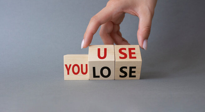 You use or lose symbol. Businessman hand Turns cube and changes word You lose to You use. Beautiful grey background. Business and You use or lose concept. Copy space