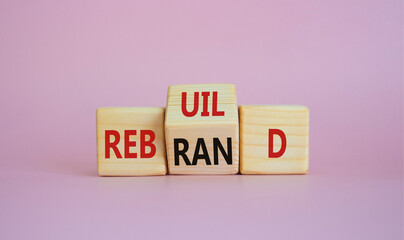 Rebuild and Rebrand symbol. Wooden cubes with words Rebrand and Rebuild. Beautiful pink background. Rebuild Rebrand and Business concept. Copy space