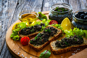 Tasty bruschetta with tapenade on wooden table
