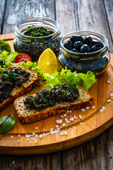 Tasty bruschetta with tapenade on wooden table
