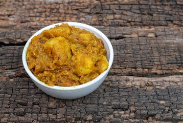Potato Dahi Curd Curry in a White Bowl Isolated on Textured Wooden Background with Copy Space