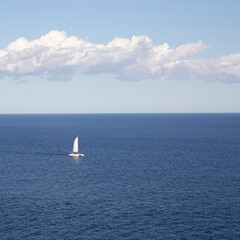 Sailboat sailing through the sea on the blue horizon
