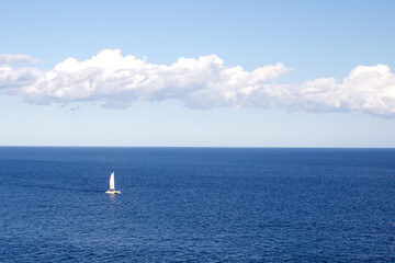 Sailboat sailing through the sea on the blue horizon