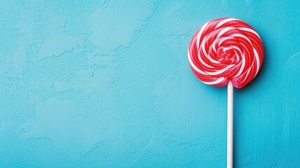 Vibrant red and white swirled lollipop on a blue textured background