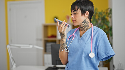 Hispanic woman with amputee arm doctor sending voice message by smartphone at clinic - obrazy, fototapety, plakaty