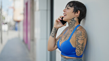 Hispanic woman with amputee arm smiling confident talking on the smartphone at street