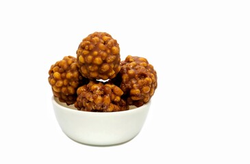Jaggery Laddu or Gur Ladoo Indian Winter Sweets in a White Bowl Isolated on White Background with Copy Space