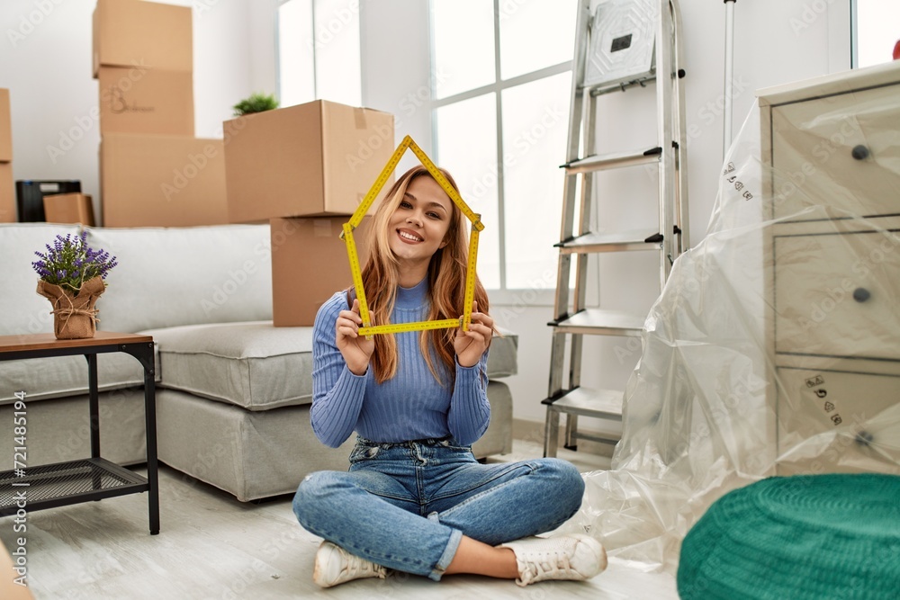 Sticker Young caucasian woman holding house project sitting on floor at new home