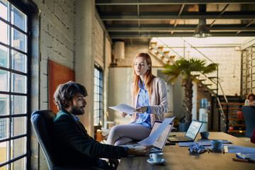Fototapeta premium Young man and woman discussing document in office