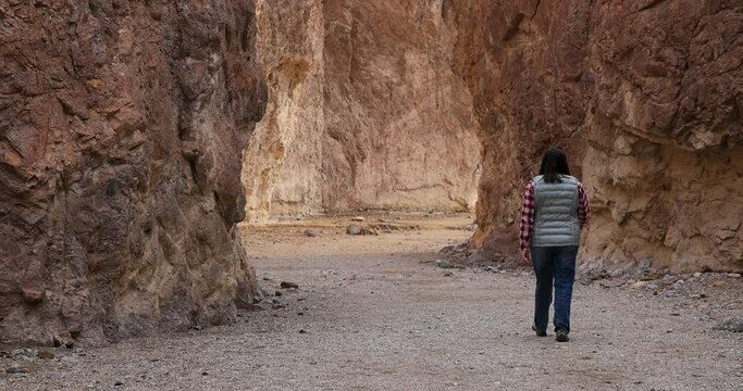 Death Valley wife hiking narrow slot canyon. Largest national park in contiguous USA. 282 feet below sea level. Mojave Desert bordering Great Basin Desert. Ecological geology. 