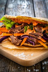 Pita - big sandwich with pulled beef and fresh vegetables on wooden table

