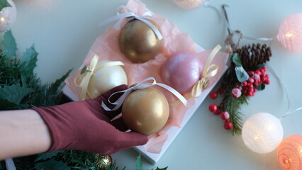 Female hand in glove stacking chocolate balls of different colors in a gift box. Chocolate balls in a box