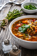 Fresh vegetable soup with lentil on wooden table

